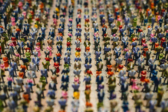 Rows of miniature people standing in line representing image of population or crowd.