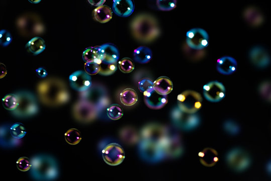 beautiful colorful soap bubbles float in the dark.