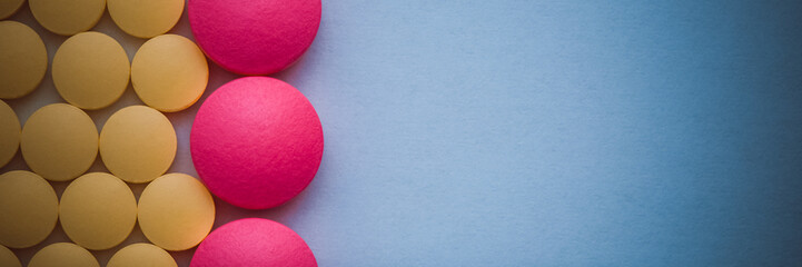 Pink and yellow pills in a row on a blue background.