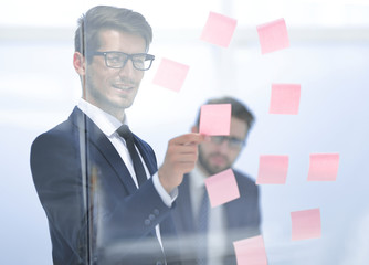serious employee reads a sticker-note on the office Board.