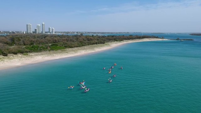 A group of people in kayaks paddling along the coastline