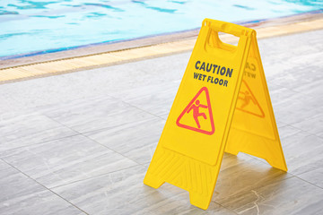 Warning plates wet floor beside the pool.