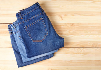 A stack of folded jeans on wooden background. 