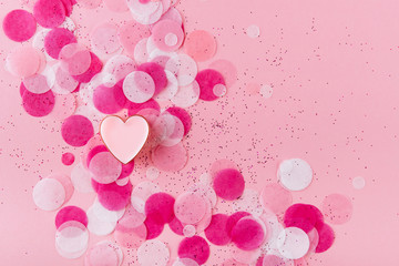 heart with confetti on pink background. Top view