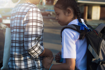 Mother and daughter are walking hand in hand to school.