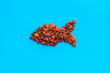 Cat food. Dry food in shape of fish on blue backgorund top view copy space