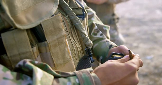 Mid section of military soldier holding rifle magazine during training 4k