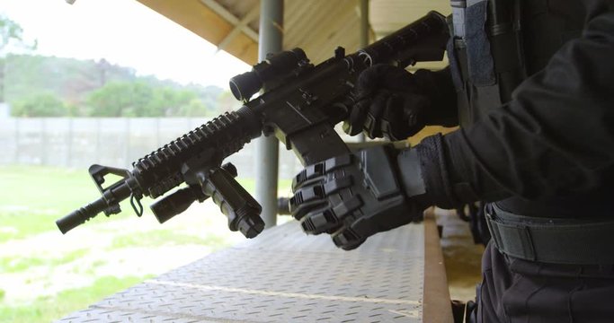 Mid section of young military soldier loading rifle magazine during military training 4k