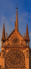 Details of the southern facade of Notre Dame de Paris Cathedral facade with the rose window and ornate spires in the warm light of sunset