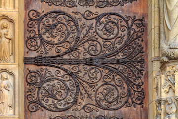 Intricate wrought iron vintage scroll work on the door hinges of Notre Dame de Paris Cathedral in...