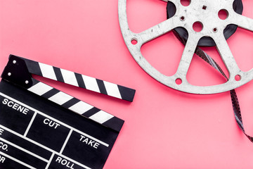 Filmings concept. Clapperboard and film stock on pink background top view copy space