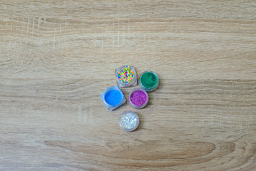 Several jars of multicolored sparkles for the design of nails or make-up on the desktop