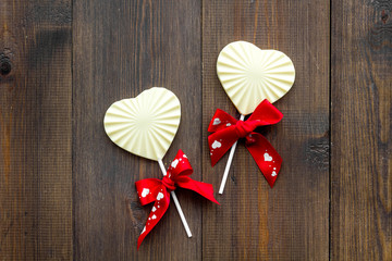 Heart-shaped lollipop for Valentine's day on dark wooden background top view space for text