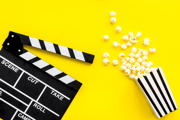 Movie premiere concept. Clapperboard and popcorn on yellow background top view space for text