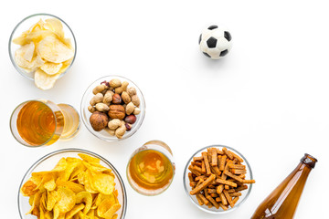 Snacks for watching football on TV. Watching sports. Chips, nuts, rusks near beer and soccer ball on white background top view copy space