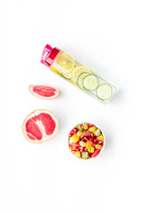 Weight loss concept. Fruit salad near fruit lemon and cucumber water on white background top view copy space
