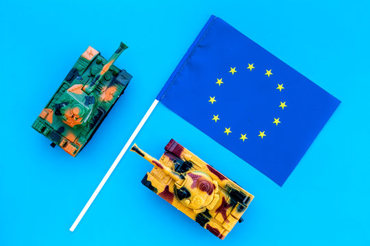 War, military threat, military power concept.European Union. Tanks toy near european flag on blue background top view