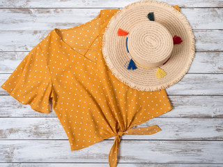 Womens clothing, accessories  (yellow blouse in polka dot, straw hat). Fashion outfit, spring summer collection. Shopping concept. Flat lay, view from above