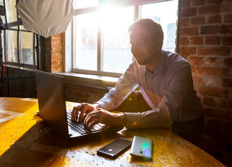Satisfied young man looks at the screen of laptop monitor. concept of freelancing in loft office