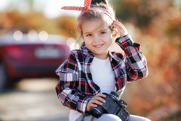Cute little girl traveling alone on a rural road on a red cabriolet. Cute little girl in a plaid...