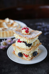 Tea and sweets on a dark background, Mille-feuille, Eclairs, Tart, Decorative with flowers, Selective focus, Closeup