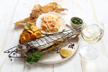 Pieczona ryba podana z surówką i opiekanymi ziemniakami. © foodandcook