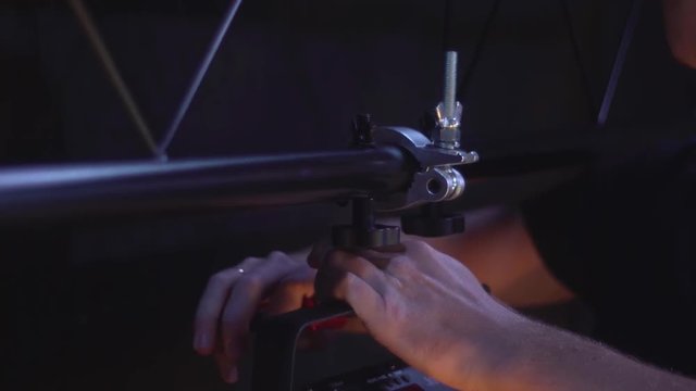 Light technician attaches the spotlight screw to the base of the stage to illuminate hall. work backstage