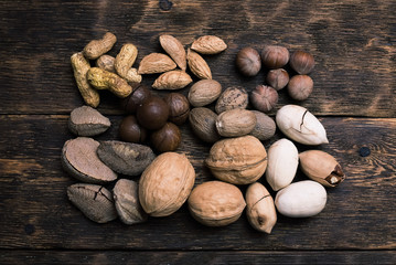 Various sorts of nuts on a brown wooden board background.