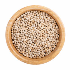 White pepper. Hot peppercorn in wooden bowl isolated on white. Top view.