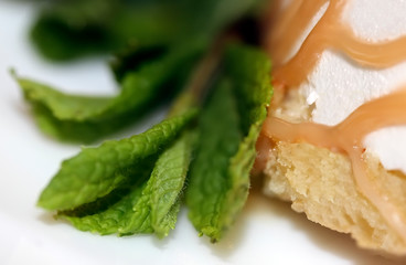 Texture , background of cake decorated with vanilla glaze and mint leaves. Close up. Macro