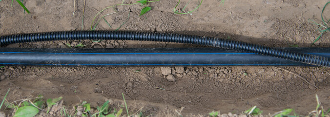 black plastic pipe for water supply to the house and electricity wire in plastic protective cover,...