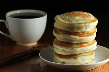 A stack of freshly backed pancakes and a cup of coffee