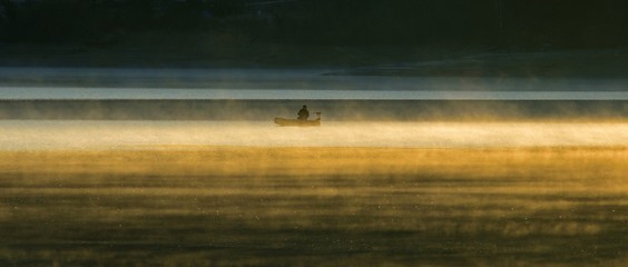 気嵐に包まれた朝の千丈寺湖で釣りをするアングラー