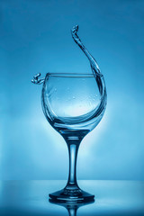 glass of splash water on blue background