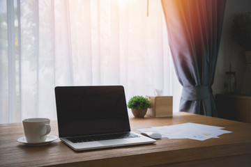 wood office table with blank screen on laptop in office room.
