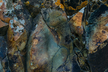 The surface of an old rock with cracks and moss. Old rock texture (wild background)