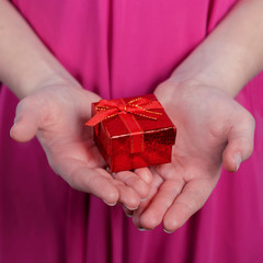 The concept of a holiday gift. A red gift box in the hands of a young woman