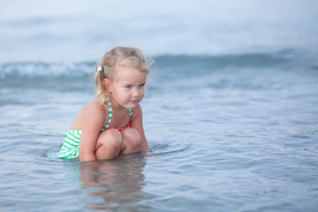 Fototapeta na wymiar Little cute happy girl swims in the sea, Spain