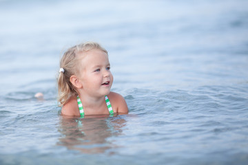 Fototapeta na wymiar Little cute happy girl swims in the sea, Spain