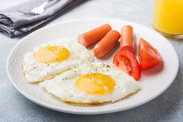 Fried eggs and sausage, tomatoes on a plate. concept breakfast