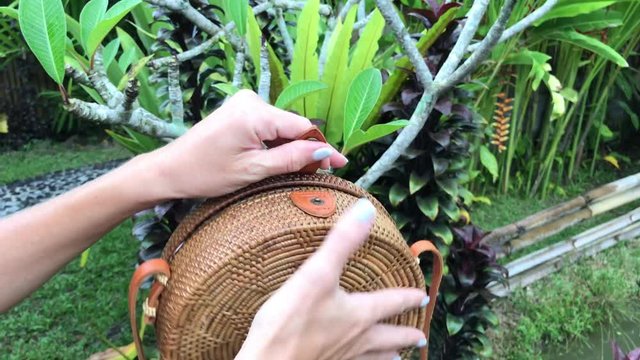 Closeup of stylish handmade rattan handbag on a tropical background. Bali island.