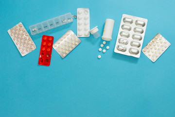 Course of treatment with atibiotics and vitamins. Variety of blisters of pills for relieving symptoms. Drugs on blue background with copy space. Medical flat lay from top view.