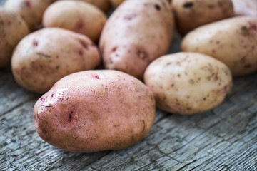 Raw unpeeled potatoes lying on the rough wooden boards