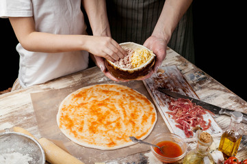 Cooking pizza with mom. Moms and daughters hands cooking homemade pizza together. Ingredients and equipment on the background of the table. Food concept