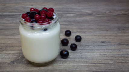 Greek yogurt, milk, smoothie with blueberries and currants in a glass jar on a wooden table, detox, diet