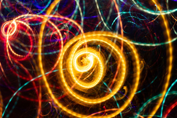 Close-up abstract glowing yellow spiral swirl on black background. 