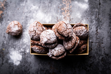 Czekoladowe makaroniki z cukrem pudrem. Apetyczne domowe wypieki na kuchennym blacie.