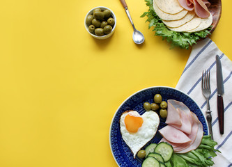 Breakfast on Valentine's Day - fried eggs and bread in the shape of a heart and fresh vegetables. Top view 