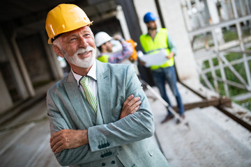 Confident construction engineer, architect, businessman in hardhat on building site