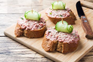 Sandwiches with chicken pate and cucumber on wooden table.